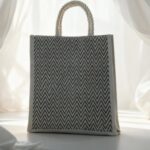 Eco-friendly jute tote bag with black zigzag pattern and rope handles by Earth Tote, displayed in natural light.