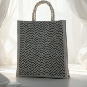 Eco-friendly jute tote bag with black zigzag pattern and rope handles by Earth Tote, displayed in natural light.