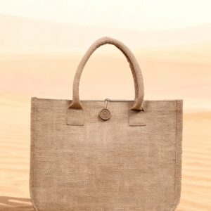 Earth Tote eco-friendly jute tote bag with button detail, displayed on sand against a desert background